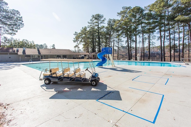 pool with a water slide, a patio area, and fence