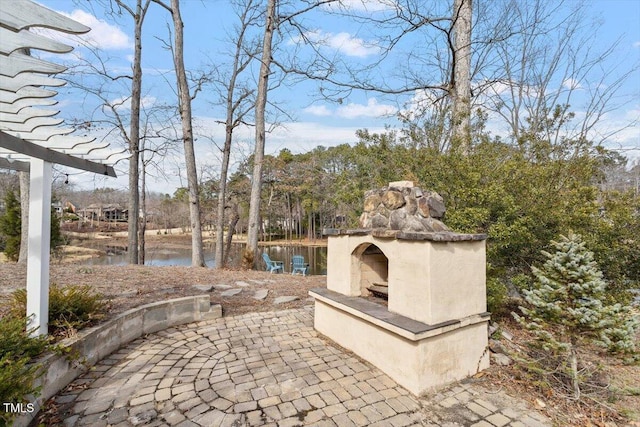 view of patio / terrace featuring a water view and an outdoor fireplace