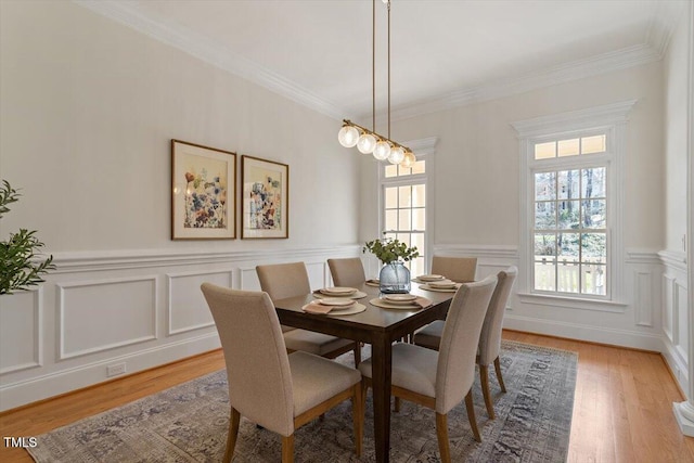 dining space featuring light wood-style floors, a wealth of natural light, and crown molding