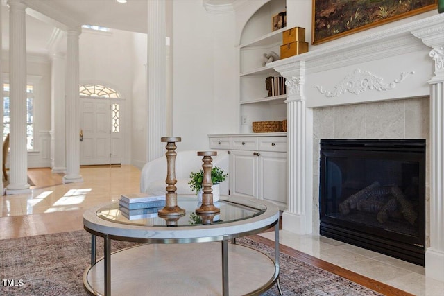 living room with built in features, a fireplace, ornate columns, and light tile patterned floors