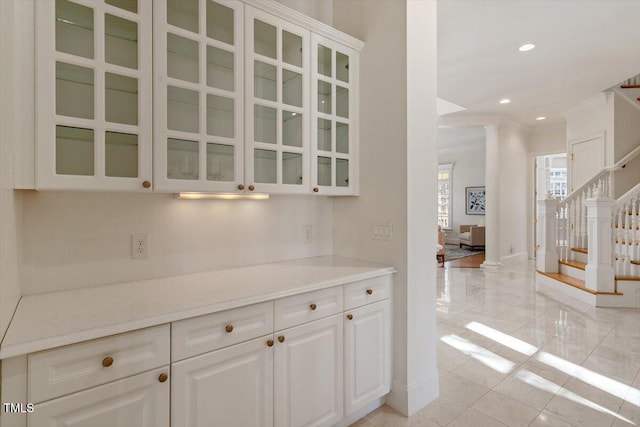 kitchen featuring decorative columns, glass insert cabinets, white cabinets, and recessed lighting