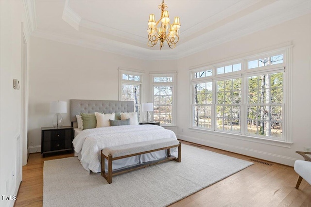 bedroom with visible vents, a raised ceiling, wood finished floors, an inviting chandelier, and crown molding