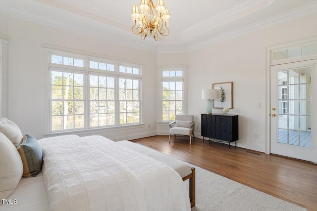 bedroom with crown molding, a notable chandelier, visible vents, wood finished floors, and baseboards