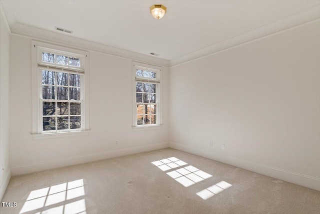 empty room featuring light carpet, ornamental molding, visible vents, and baseboards