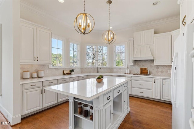 kitchen featuring white cabinets, custom range hood, a center island, light countertops, and open shelves