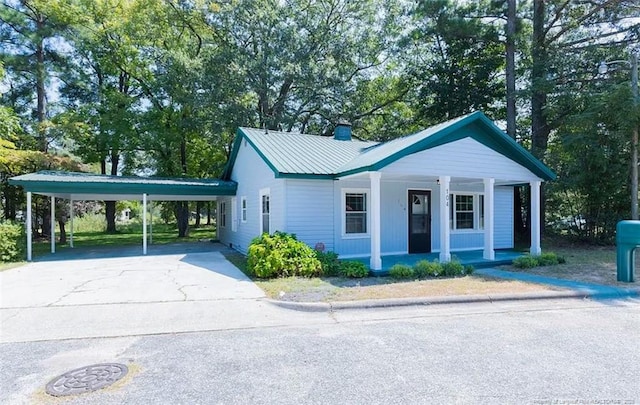 view of front of house with metal roof, a porch, and concrete driveway