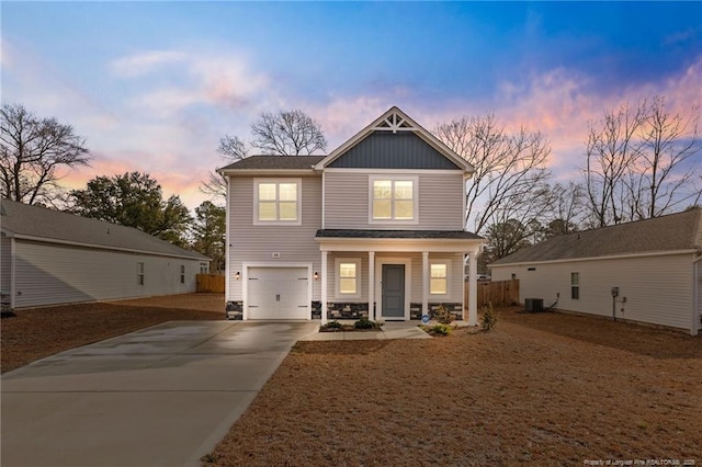 view of front of property with central AC unit, a garage, covered porch, driveway, and board and batten siding