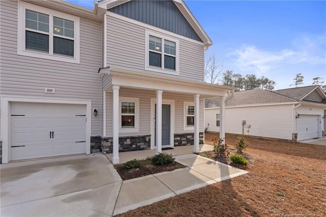 view of front of property with covered porch, board and batten siding, a garage, stone siding, and driveway