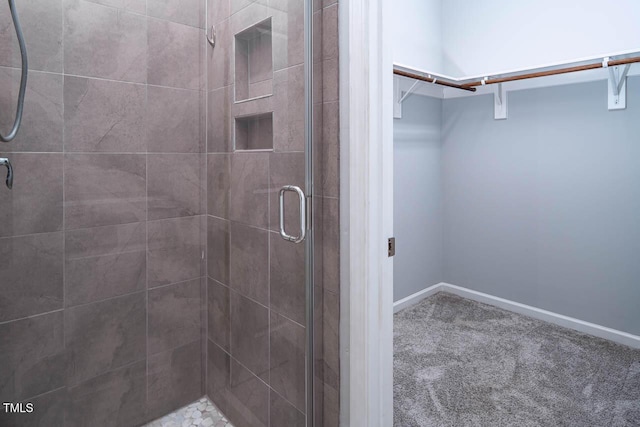 full bathroom with baseboards, a spacious closet, and a shower stall