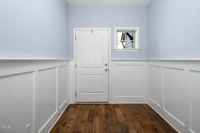 doorway to outside featuring a decorative wall, dark wood-style floors, and a wainscoted wall