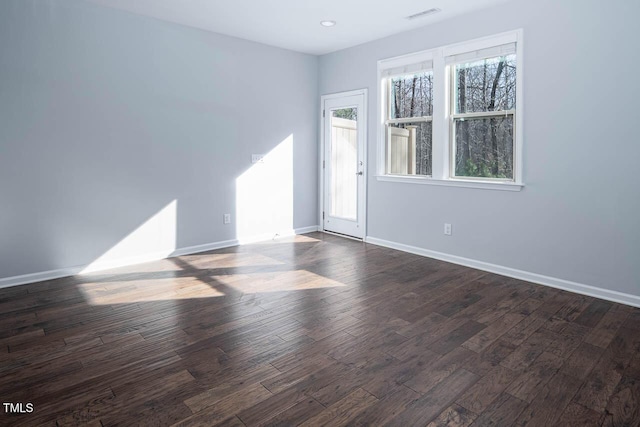 spare room featuring dark wood-type flooring, baseboards, and visible vents