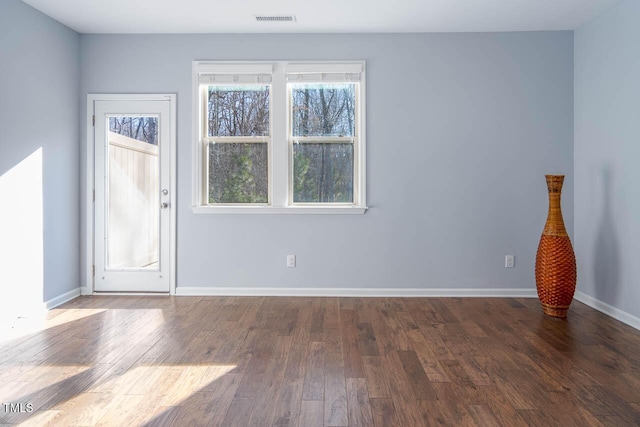 unfurnished room with visible vents, baseboards, and wood finished floors