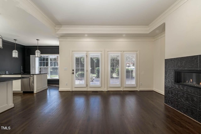 unfurnished living room featuring a wealth of natural light, dark wood finished floors, a fireplace, and ornamental molding