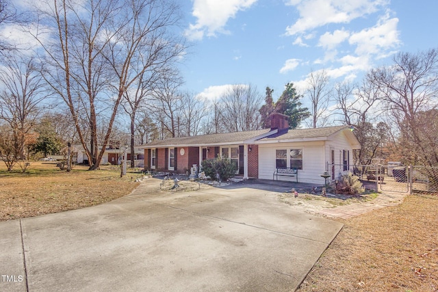 single story home featuring a chimney, a front lawn, and concrete driveway