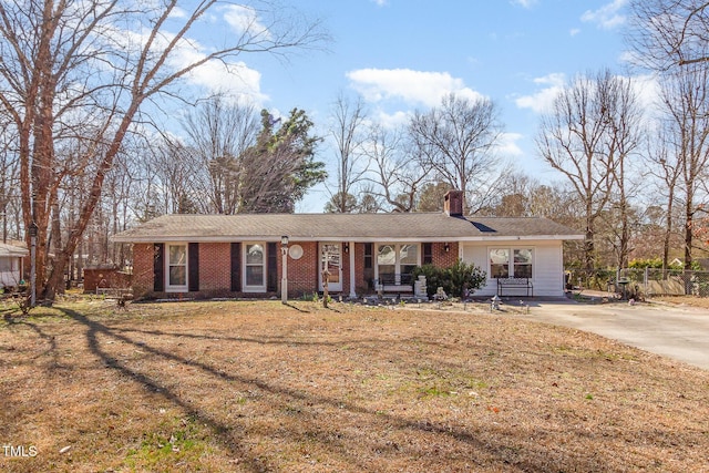 ranch-style house featuring a chimney, a front lawn, and brick siding