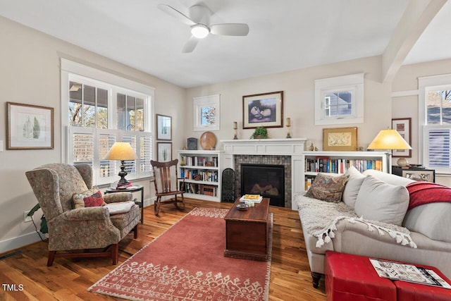 living area with a brick fireplace, baseboards, and wood finished floors