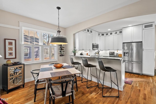 kitchen with stainless steel appliances, arched walkways, a peninsula, a breakfast bar area, and glass insert cabinets