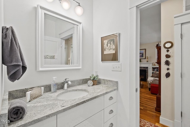 bathroom with vanity, wood finished floors, and a fireplace