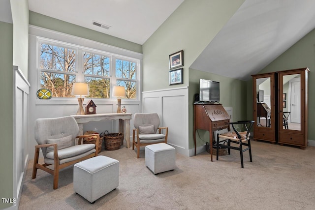 sitting room featuring visible vents, carpet, wainscoting, and vaulted ceiling