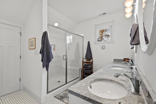 full bath with a sink, visible vents, a stall shower, and double vanity