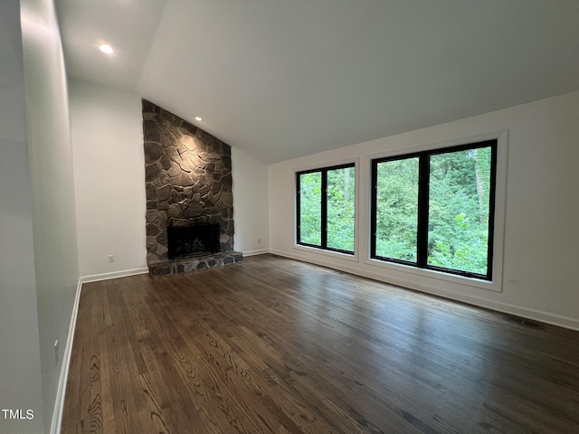 unfurnished living room featuring dark wood-style floors, baseboards, vaulted ceiling, and a stone fireplace