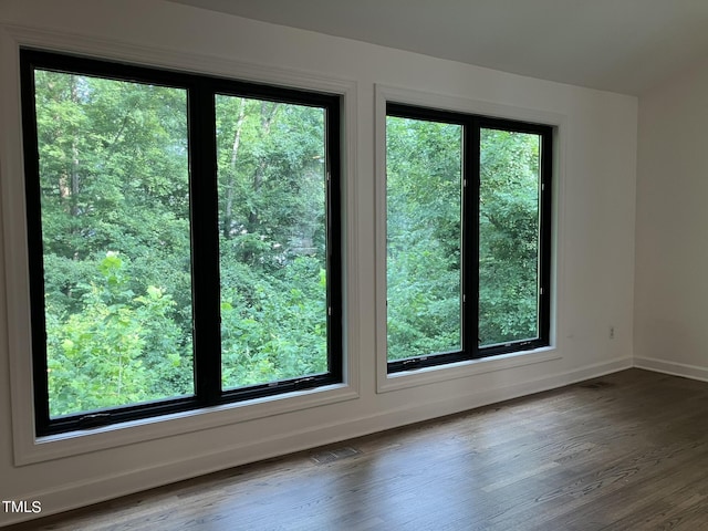 spare room with dark wood-style floors, visible vents, and baseboards