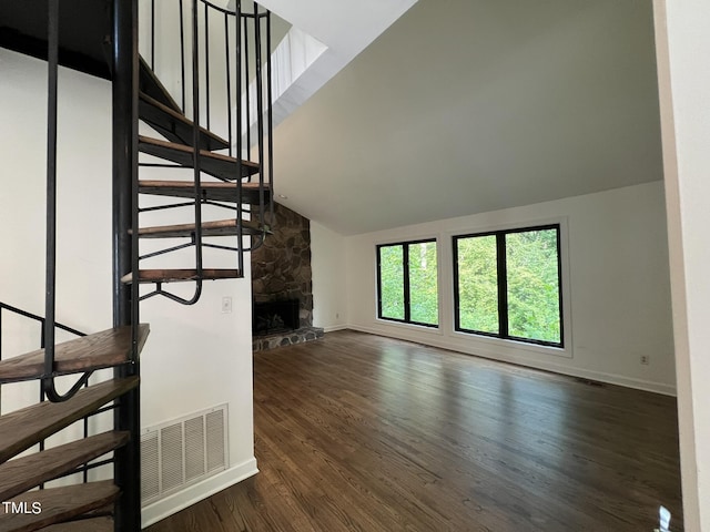 staircase with a fireplace, wood finished floors, visible vents, baseboards, and vaulted ceiling