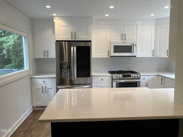 kitchen featuring stainless steel appliances, dark wood-style flooring, white cabinetry, light countertops, and tasteful backsplash