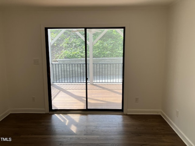 spare room with dark wood-style floors, crown molding, and baseboards