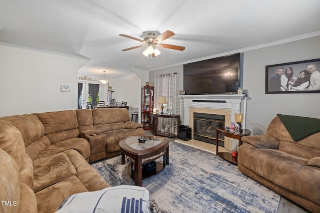 living room featuring a glass covered fireplace, crown molding, and a textured ceiling