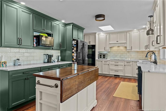 kitchen featuring dark wood-type flooring, a skylight, white cabinetry, black appliances, and green cabinetry