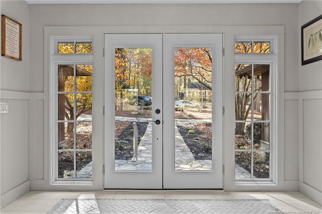 doorway to outside featuring french doors, a decorative wall, and a healthy amount of sunlight