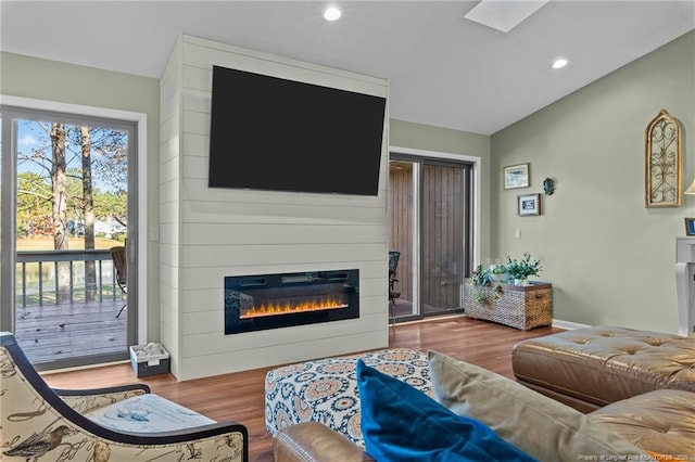 living area with a large fireplace, a skylight, wood finished floors, and recessed lighting