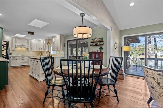 dining area with a skylight, light wood-style flooring, and recessed lighting