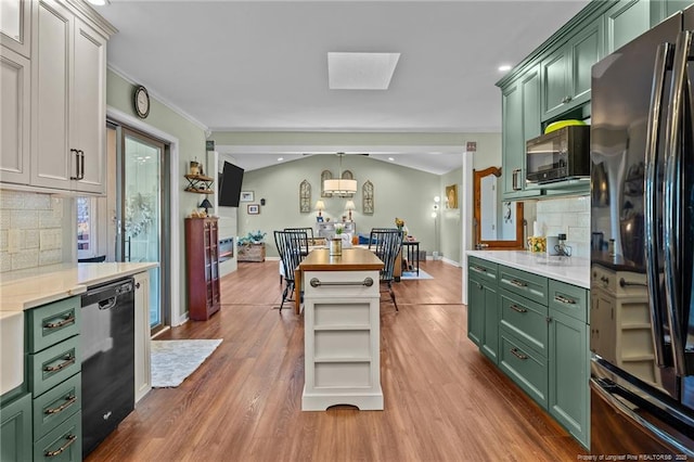 kitchen featuring wood finished floors, light countertops, hanging light fixtures, black appliances, and green cabinetry