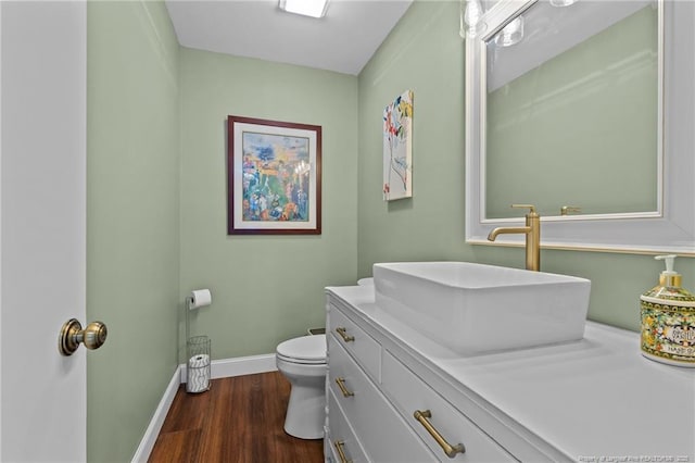 bathroom with toilet, wood finished floors, vanity, and baseboards