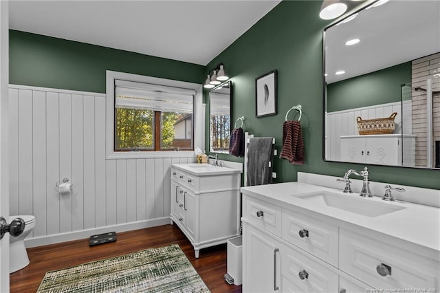 full bath with a wainscoted wall, two vanities, a sink, and wood finished floors