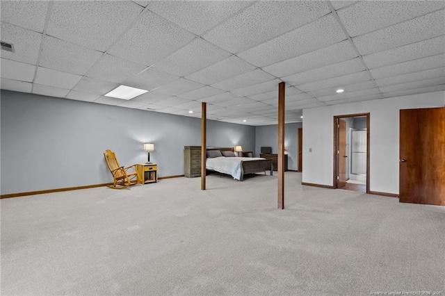 unfurnished bedroom with a paneled ceiling, light colored carpet, and baseboards