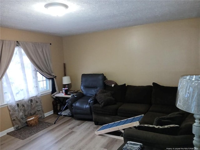 living area featuring light wood-style floors, baseboards, and a textured ceiling