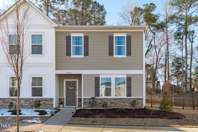 view of front of home featuring stone siding and fence