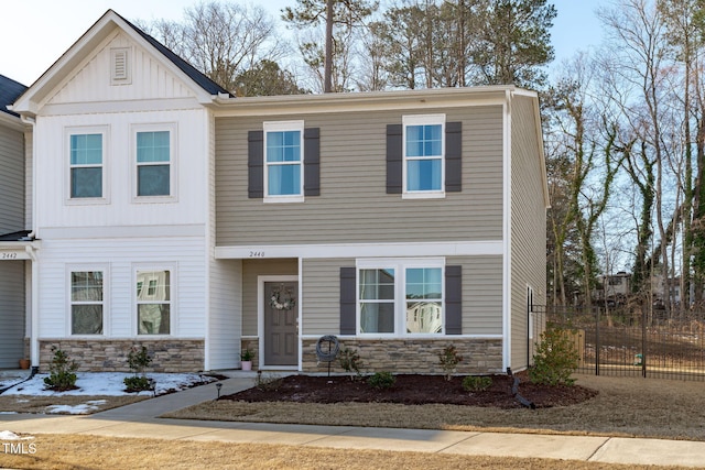 view of front of home with stone siding, board and batten siding, and fence