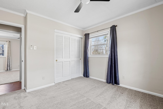 unfurnished bedroom with crown molding, a closet, baseboards, and carpet flooring