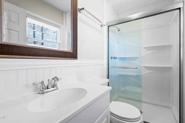 bathroom featuring a stall shower, wainscoting, vanity, and toilet