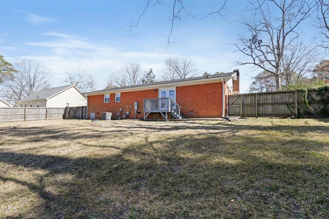 rear view of house with crawl space, brick siding, a yard, and a fenced backyard