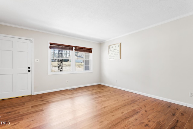 unfurnished room featuring a textured ceiling, wood finished floors, visible vents, baseboards, and ornamental molding