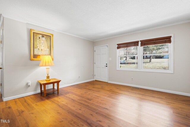 entrance foyer featuring ornamental molding, visible vents, baseboards, and hardwood / wood-style flooring