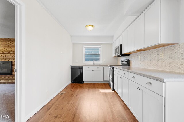 kitchen featuring stainless steel appliances, a sink, white cabinetry, light countertops, and light wood-type flooring