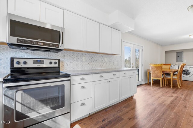 kitchen with stainless steel appliances, washer / clothes dryer, electric panel, and tasteful backsplash