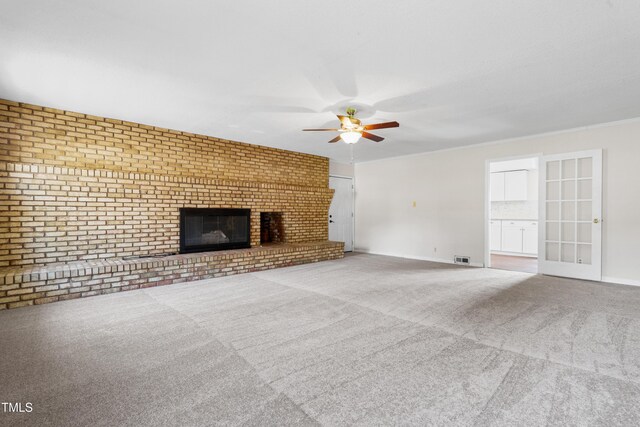 unfurnished living room with baseboards, a ceiling fan, brick wall, carpet, and a fireplace