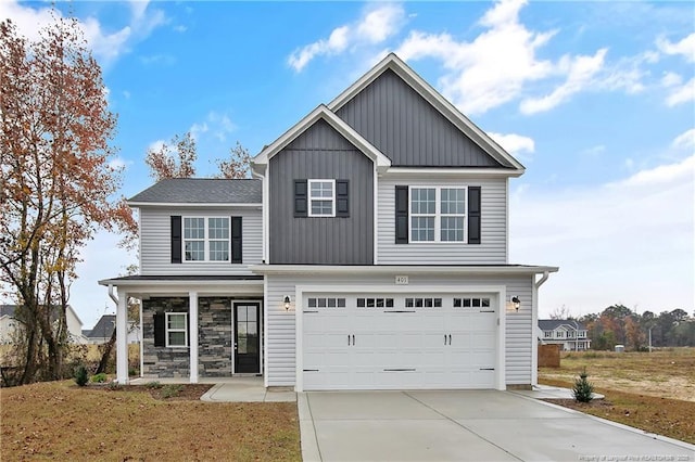 traditional home with a porch, an attached garage, concrete driveway, stone siding, and board and batten siding